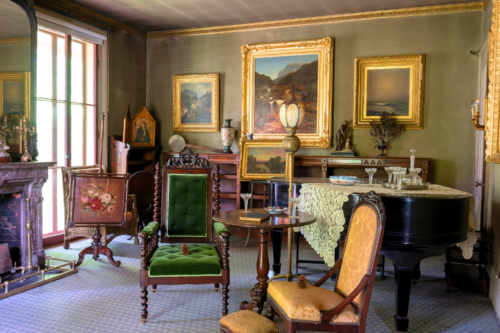 parlor of evergreens with furniture, piano and paintings
