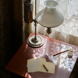 Dickinson's writing desk with pens, scraps of paper and her lamp